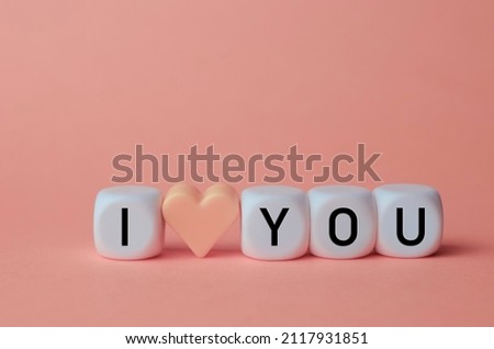 I love you concept on pink background. Black letters on white cubes and a heart. Declaration of love.