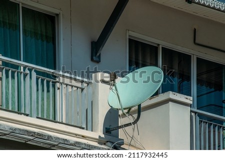 A soft mint green satellite dish or antenna at the white balcony in apartment, dormitory, house with a curtain in light and shadow background. Street artwork minimal design backdrop lifestyle concept.