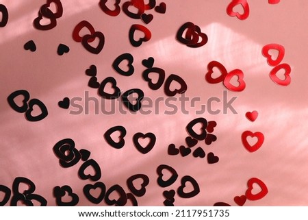 Red heart shaped confetti on pastel pink background. Flat lay. 