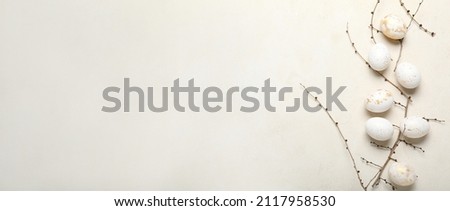 Beautiful Easter eggs and tree branches on light background with space for text