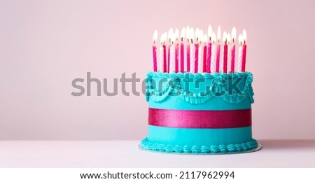 Blue birthday cake with buttercream piping, pink ribbon and pink birthday candles
