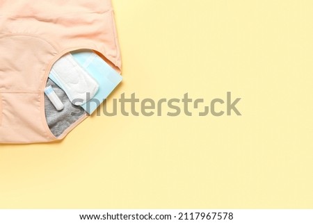 Period panties, pads and tampon on color background, closeup