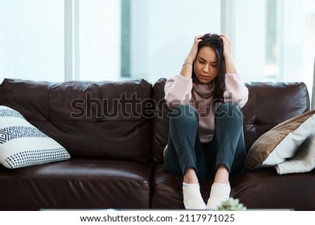 Somebody make it stop. Shot of a young woman experiencing mental anguish at home. Royalty-Free Stock Photo #2117971025