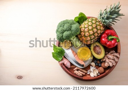 Round tray with anti-inflammatory and antioxidant food, healthy eating for the immune system with fiber, vitamin, omega-3 and minerals, light wooden background, copy space, top view from above Royalty-Free Stock Photo #2117972600