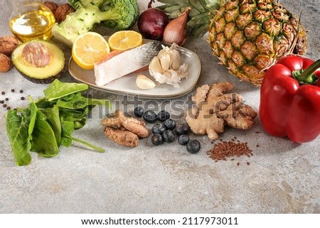 Fresh vegetables, fish, fruits, nuts and spices for an anti-inflammatory and antioxidant diet, healthy food concept, light gray stone background with copy space, selected focus, narrow depth of field Royalty-Free Stock Photo #2117973011