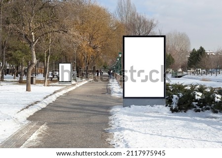 Blank billboard in snowy weather in a public park