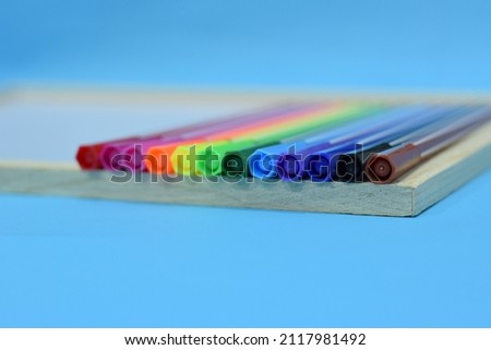 Selective Focus of A Set of Colourful Magic Pens On A Wooden White Board Isolated with Blue Background. Soft Focus over Pen's Cap