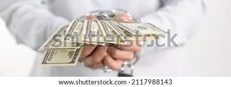 Woman with hands tied metal chain holding many dollar bills closeup. Fraud and bribery concept