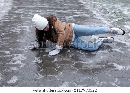 Young woman fallen on slippery icy pavement outdoors Royalty-Free Stock Photo #2117990522