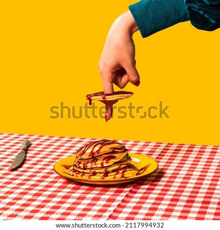 Tasting. Food pop art photography. Female hand and sweet pancakes on plaid tablecloth isolated on bright yellow background. Vintage, retro 80s, 70s style. Complementary colors, Copy space for ad, text