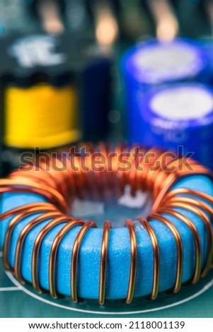 Electronic component, induction coil with copper wire winding on magnetic ferrite core on circuit board Royalty-Free Stock Photo #2118001139