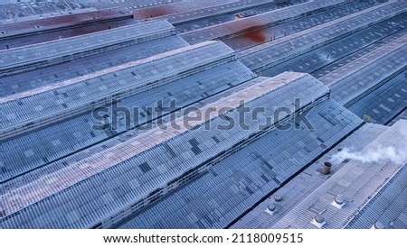 Roofs of Factory buildings in heavy industrial with white smoke against blue sky during sunset. Aerial photo view by drone from top of plant.