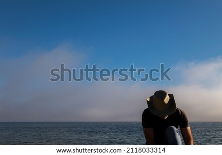 Adult man in cowboy hat and jeans on beach against sea and sky. Almeria, Spain