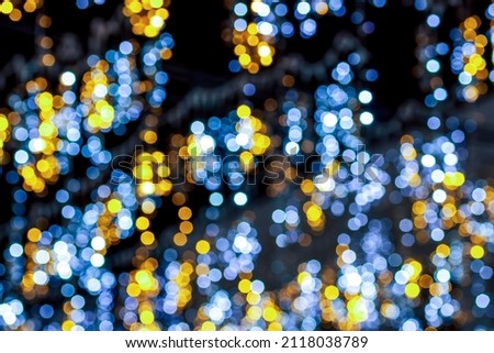 blurred defocused night lights of city on black background, abstract garland shine close up , blue and yellow small round light