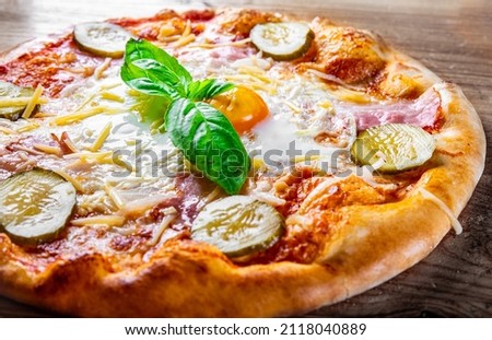 Pizza o sole mio with baked egg and ham. Italian pizza on wooden background