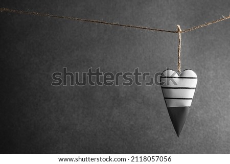 a black and white heart hangs on a rope on a gray background. Valentine's Day, Love. with copy space