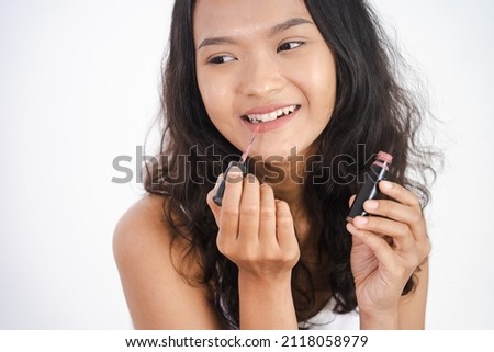 woman applying lipstick on her lip on white background