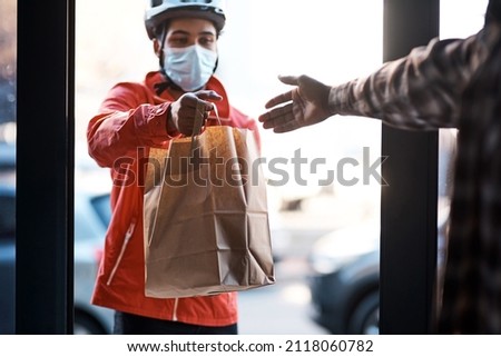 We've got you covered during lockdown. Shot of a masked man delivering a food package. Royalty-Free Stock Photo #2118060782