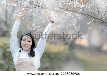 Happy woman standing under the tree  open hands above head ,touching tree ,,selective focus .Relaxion concept.
