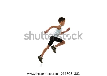 Side view portrait of little boy in motion, running isolated over white studio background. Concept of action, sport, healthy life, competition, motion, physical activity. Copy space for ad Royalty-Free Stock Photo #2118081383