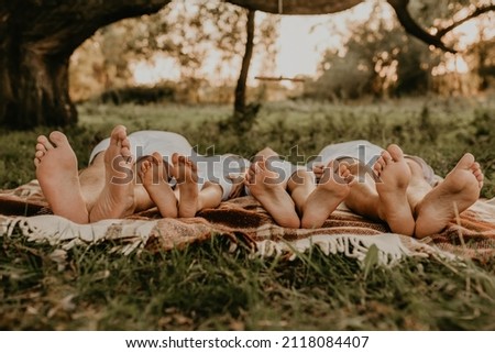 close-up bare feet of whole family resting. cheerful happy family dad mom daughters lay laying on grass picnic plaid have fun at summer outdoors together. father mother sisters parents barefoot people Royalty-Free Stock Photo #2118084407