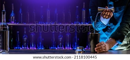 Bartender's hands shaking cocktails on bar counter in a restaurant, pub. Professional mixologist mixing drinks. Alcoholic cooler beverage at nightclub. Selected focus, shallow depth of field.