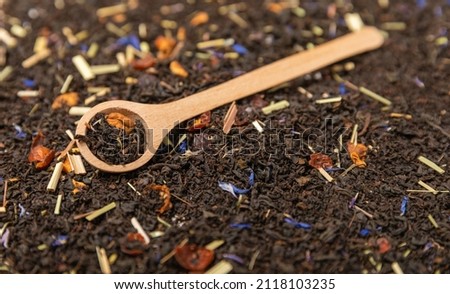 Background of black tea leaves with pieces of fruit. wooden spoon with tea.Top view.Copy space.