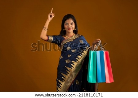 Beautiful Indian young girl or woman holding and posing with shopping bags on a brown background