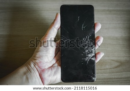 broken screen smarthphone on black background with hand