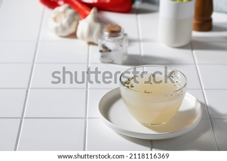 Healthy golden bone broth with spices in a mug on a saucer on a white background. The concept of keto diets. Copy space.
