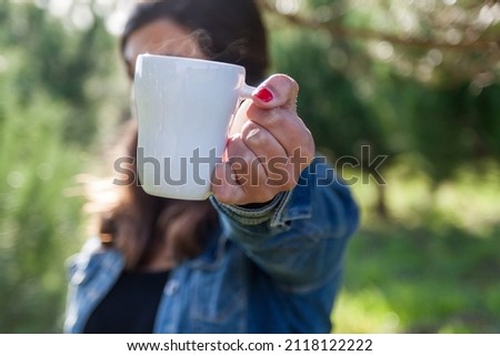 Woman holding a white mug in the middle of the nature. High quality photo