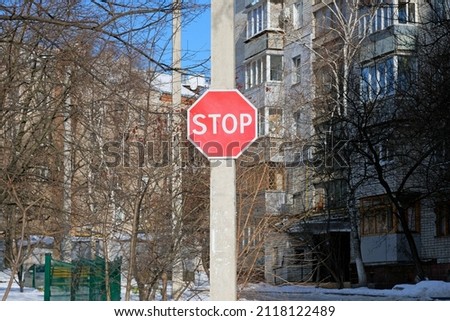 A red stop sign on a pole in the courtyard of a residential complex. Road sign traffic without stopping is prohibited in the yard of an apartment building. 