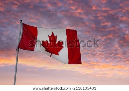 Flag of Canada flying on a pole against a sunrise background. Royalty-Free Stock Photo #2118135431