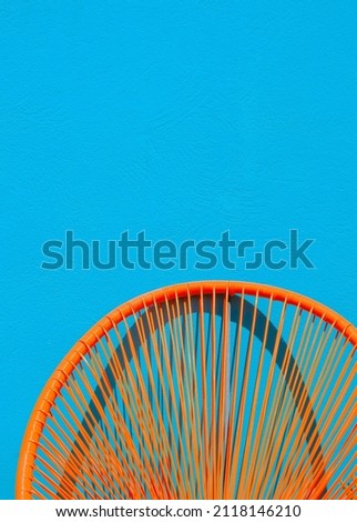 Summer armchair against a blue wall. Home decor in detail. Minimalist aesthetic