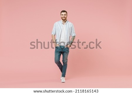 Full length young happy cheerful friendly caucasian unshaven man 20s in blue striped shirt white t-shirt look camera isolated on pastel pink color background studio portrait. People lifestyle concept Royalty-Free Stock Photo #2118165143