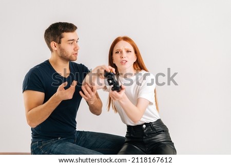 Studio shot of young man trying to draw attention of woman playing video games on white isolated background. Concept of relationship crisis.