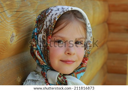 Outdoor image of beautiful smiley little girl wearing Pavloposadsky scarf over wooden background at summer 