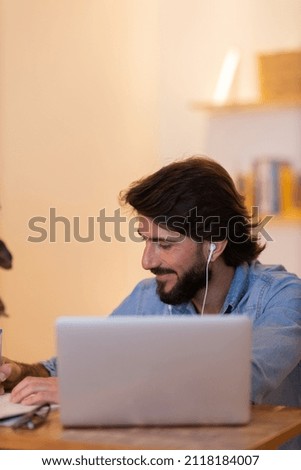 Young business man working at home with laptop and papers on desk. Gray notebook for working and white headphones. Home office concept. High quality photo