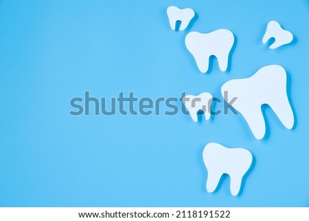 Paper cut mockup of tooth on blue background. Dental care concept. International Dentist Day. Greeting card for professional holiday.