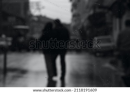 Loving couple behind water drops on glass, close-up blurry image, selective focus, black and white photo