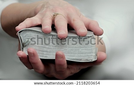 praying with hand on bible black grey background stock photo