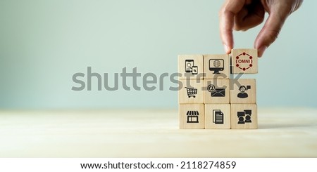 Omnichannel marketing concept. Digital online marketing commerce sale. For customer engagement by integrated online and offline channels. Hand holds wooden cube with omni text standing with omni icon Royalty-Free Stock Photo #2118274859
