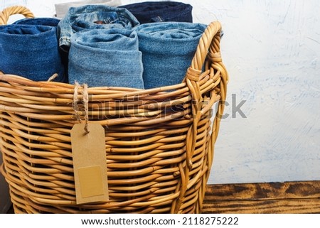 jeans and a belt in a wicker basket on a wooden table. with a ta