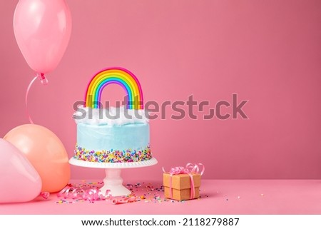 Blue Birthday Cake with party balloons and gift on Pink