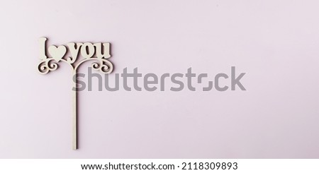 A wooden axe with the words I LOVE YOU on a pink background. Copy space.
