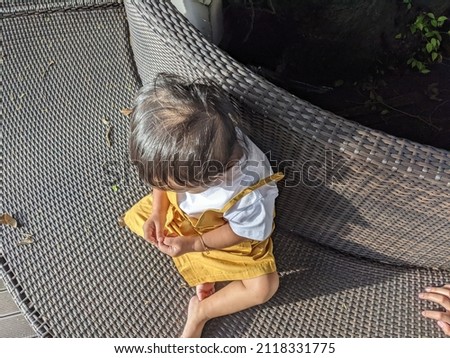 little girl sitting on the park and fountain fish pond on the sun light. The photos is perfect for poster, pamphlet and banner about holiday on the hotels.