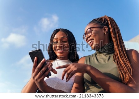 two young african women having fun looking at the cell phone, concept of youth and communication technology, copy space for text Royalty-Free Stock Photo #2118343373