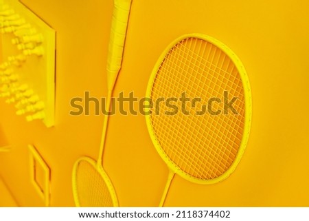 Badminton rackets painted yellow are located against the background of an orange wall. Decoration of the room with the help of unnecessary items. selective focus