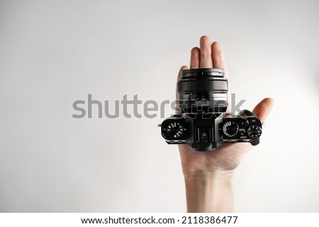 a man holds a compact modern mirrorless  camera on his hand on a white background top view Royalty-Free Stock Photo #2118386477