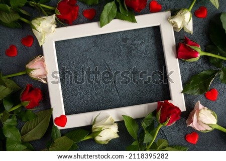 Red and white roses with a photo frame for Valentine's Day, marriage proposal engagement, birthday, anniversary, wedding, Mother's Day. Love composition with copy space on dark background.